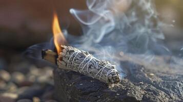 A closeup of a burning smudge stick used to cleanse and purify a space before an energy healing session. The smoke rising from the stick is believed to carry negative energ photo