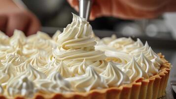 A person meticulously applies white frosting to a cake using a piping bag, creating beautiful decorations on the dessert photo