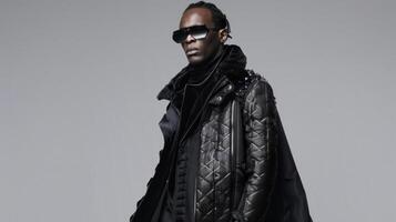 A black man makes a statement in a sleek allblack ensemble that boasts bold and futuristic silhouettes. His long coat is adorned with geometric patterns and metallic accents while photo