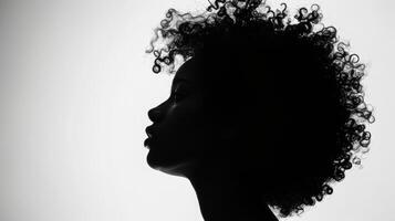 The silhouette of a woman against a bright white background her curls and curves creating a stunning contrast against the blank canvas. This photo symbolizes the endless possibilities