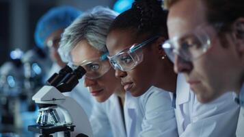 A group of scientists huddled together in a laboratory their eyes focused on a microscope as they yze and discuss the results of their research their white coats and safety goggles photo