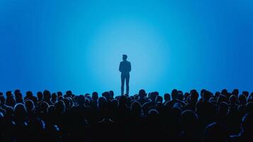 A silhouette of a person standing on a stage surrounded by a sea of audience members. This skilled negotiator has captured the attention of the entire room as they deliver a persuasive photo