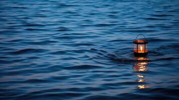 A lone lantern stands in the shallow waters as the tide rolls in, its flame burning brightly against the dark blue sea. The simplicity of the scene is a beautiful contrast to the vastness photo