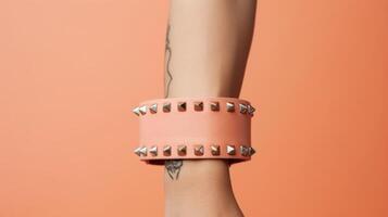 Minimalistic view of a punk rock accessory, a Peach Fuzz colored bandana tied around a studded leather wrist cuff. photo