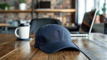 Closeup of a baseball cap mockup on a wooden table with a coffee mug and laptop in the background. Great for advertising your trendy headwear collection photo