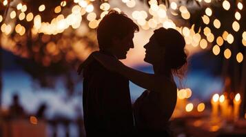 A couple dances on the terrace silhouettes illuminated by the soft glow of candlelight. . photo