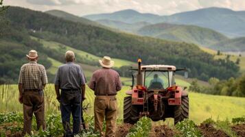 A group of older farmers backs turned to the camera gather around a tractor as they make plans for the days work. The rolling . photo