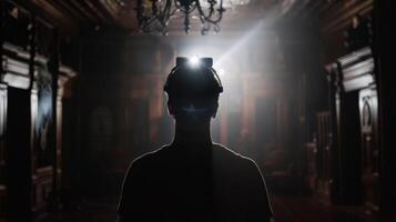 A person wearing a headlamp stands with back to the camera silhouette illuminated against the dark and foreboding interior . photo