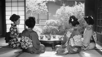 A group of friends sit on cushions around a low round table each with back to the camera engrossed in a traditional tea ceremony. . photo