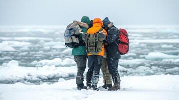 A small group of friends huddle together backs to the camera as they navigate way through a field of ice and snowdrifts. . photo