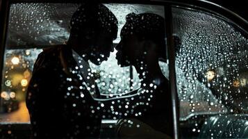 A silhouette of a black couple can be seen through the rainstreaked glass of a vintage car window. With her hand pressed against the glass and his arm wrapped protectively around her photo