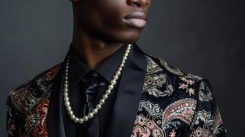 A dapper black man exudes sophistication in a tailored suit with Persianinspired prints and patterns. The addition of a string of pearls around his neck adds a touch of elegance and photo