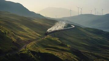 The train is seen travelling through a winding mountain pass leaving behind a trail of dark smokefree steam. The mountainside is dotted with wind turbines and solar panels indicating photo