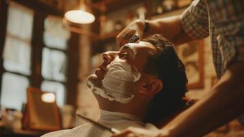 In a traditional barbershop setting a barber deftly wields his clippers to give his client a smooth and clean shave. The peaceful expression on the clients face captures the relaxed photo