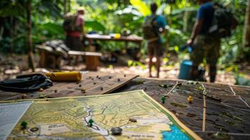 A map laid out on a makeshift table depicts the various trails and landmarks of the rainforest. In the background a group of fieldworkers can be seen setting up equipment and preparing photo