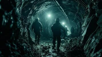 In a dimly lit tunnel silhouettes of miners can be seen scurrying about their headlamps creating a haunting glow. The cool tones of the rocks and the faint reflections of the lamps photo