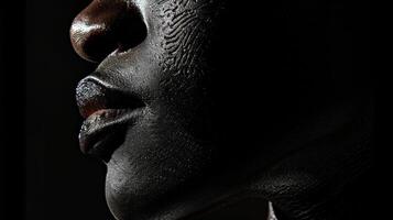 Against a black background the shadows reveal the subtle contours of the skin creating a mesmerizing contrast of light and dark. photo