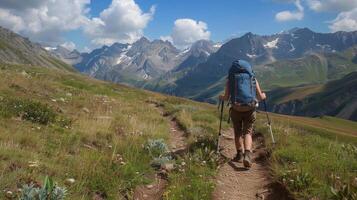 A lone hiker treks along a narrow path back facing the camera as they conquer the steep terrain of a stunning mountain range. . photo
