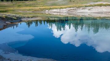 The bubbling cauldron of a fumarole casts a mirrorlike reflection on the still surface of a nearby lake photo