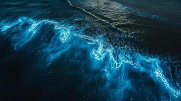 From a birds eye view the bioluminescent waves create a mesmerizing pattern giving the illusion of a glowing blue serpent in the ocean photo