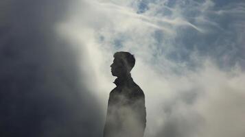 A mysterious silhouette enveloped in a cloudy embrace its shadow mirroring its every move photo