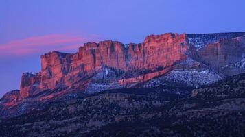 The rocky cliffs are transformed into shades of pink and purple by the gentle alpenglow making them appear almost otherworldly photo