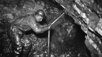 A miner using a pickaxe to chip away at the walls of the mine revealing layers of shiny coal photo
