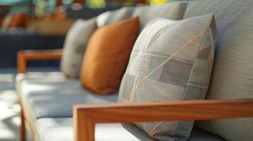 A sleek and modern outdoor sofa featuring a minimalist design and cushions made from recycled polyester fabric. The frame is made from sustainably sourced teak wood adding warmth t photo