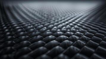 A closeup of a carbon fiber surface reveals a rich dark texture with small raised squares that give off a subtle sheen. The pattern is tight and precise exuding strength and durability photo
