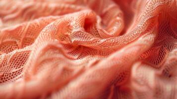 A closeup of a bright coral viscose fabric reveals an intricate weave pattern and a buttery soft texture that would be a joy to wear photo