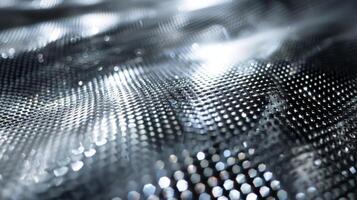 A shiny silver metal mesh reflecting the light in small dots and lines across its surface photo