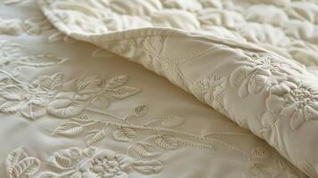 Rows of delicately stitched flowers and leaves adorn this quilted bedspread adding a feminine touch to the smooth ivory fabric. The texture is smooth to the touch perfect for a restfu photo