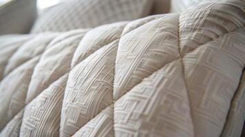 This closeup image showcases a neutraltoned quilted fabric headboard. The tightly woven fabric creates a smooth and sleek surface while the subtle diamond quilting adds a subtle touc photo