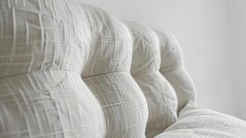 Against a white background the closeup of this quilted fabric headboard reveals a clean and crisp texture. The tightly quilted fabric creates a smooth and uniform surface perfect fo photo