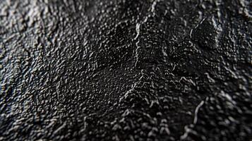 A macro shot of matte black metal displaying a bumpy speckled texture with a matte nonreflective quality photo