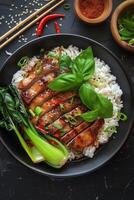 Grilled Chicken With Rice, Basil, and Bok Choy on Black Plate photo