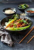 Black Bowl of Rice With Bok Choy, Spicy Sauce, and Sesame Seeds photo