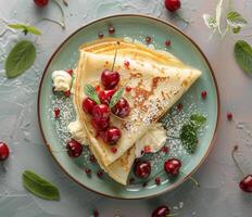 cerca arriba de un apilar de crepes con cerezas y azotado crema en un gris cuenco foto