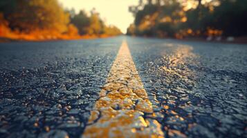 A Close-Up View of a Paved Road With a Yellow Line at Sunset photo