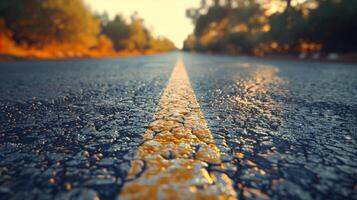 un de cerca ver de un pavimentado la carretera con un amarillo línea a puesta de sol foto