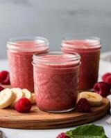 Three Mason Jars Filled With Raspberry Banana Smoothie photo