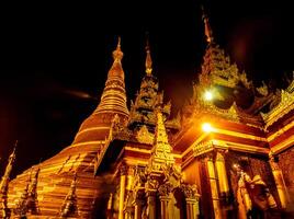 The golden pagodas and mondops are illuminated in the light of the night photo