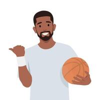 Young man holding basketball ball looking and pointing to the side with thumb up. vector
