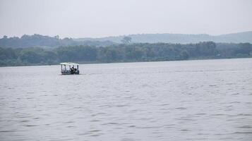 View from a distance of a boat carrying tourists at Gondang Reservoir sailing around the reservoir before passengers arrive. photo