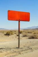 Red metal blank road sign, desert road, sunny day, copy space photo