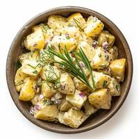 Top view of a bowl of potato salad with herbs isolated on white background photo