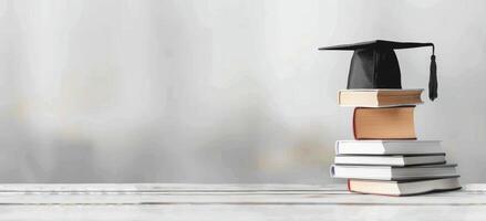 Graduation Cap Atop Stack of Books Near Window photo