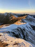 Golden Sunset Over Snow-Capped Mountain Ridges. The Tranquil Beauty Of A Remote Landscape. Adventure, Nature, And Serenity. The Tatry Mountains, Zakopane, Poland, 13 December 2024 photo