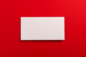 Blank white business card on red background. Mockup business card. Top view. Copy space. photo