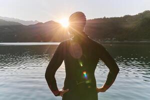 Authentic triathlon athlete getting ready for swimming training on lake photo